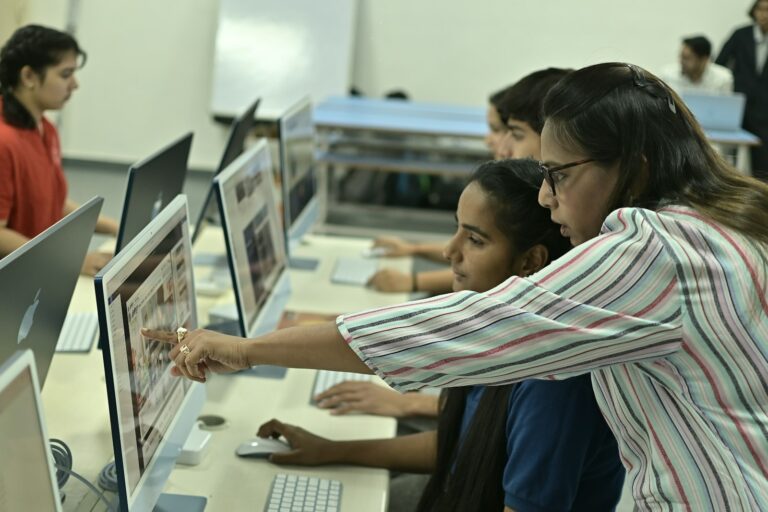 Teacher demonstrating AI skills for teachers while guiding students on a classroom laptop