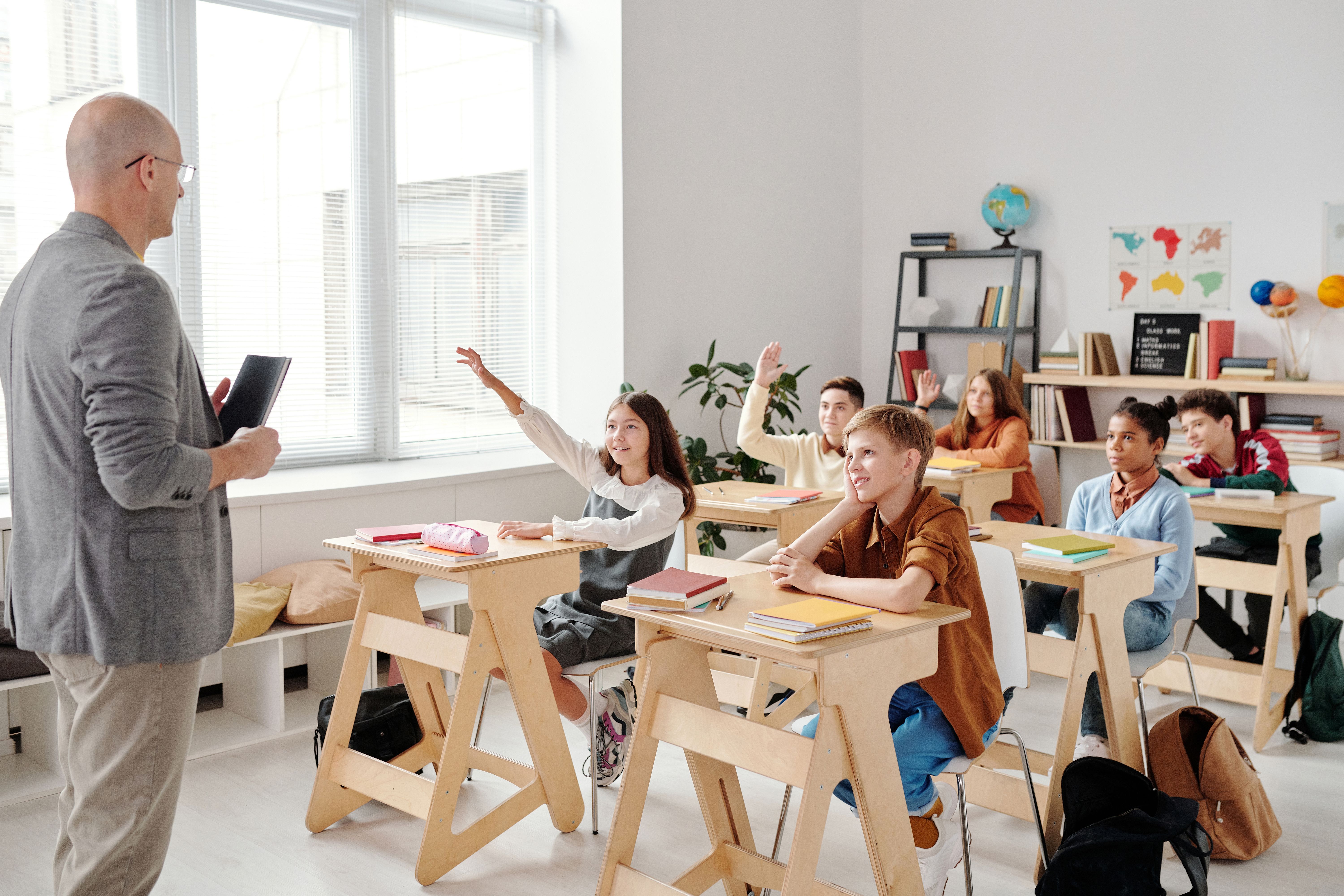Mixed-ability students raising hands in a classroom, showing differentiated instruction with AI meeting varied learner levels