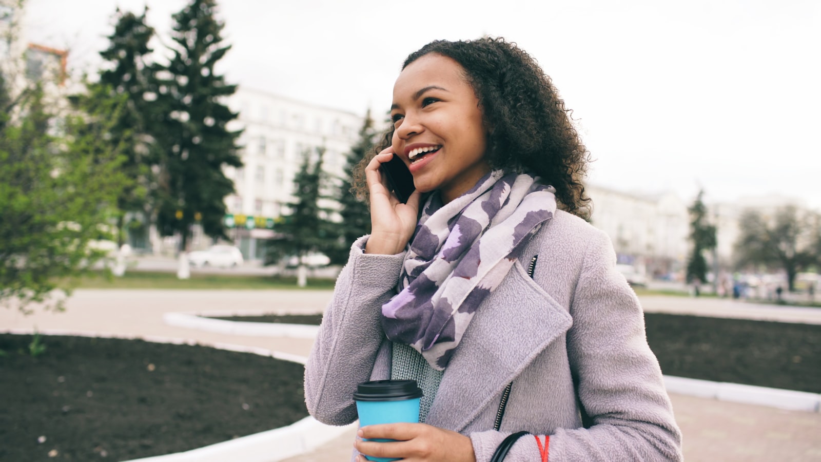 Young woman practicing spoken English outdoors using an AI speaking partner app on her phone