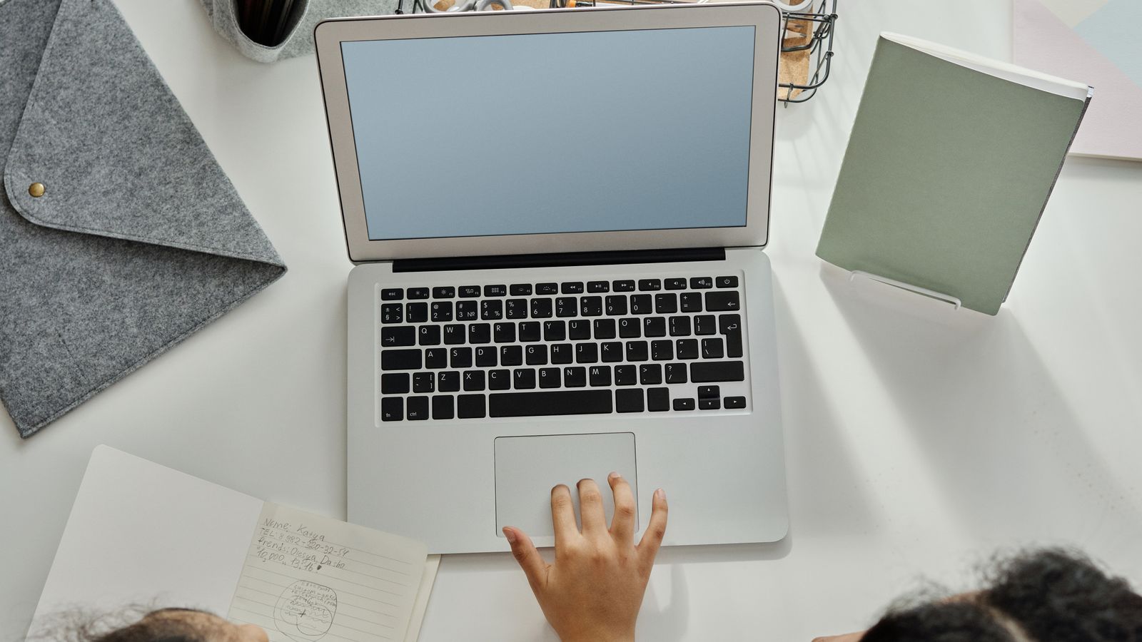 Two English language learners reviewing printed adapted materials next to a laptop