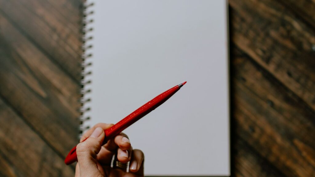 Red correcting pen resting on an open notebook ready for ESL writing corrections