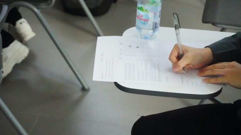 Candidate handwriting an IELTS essay under timed exam conditions on paper