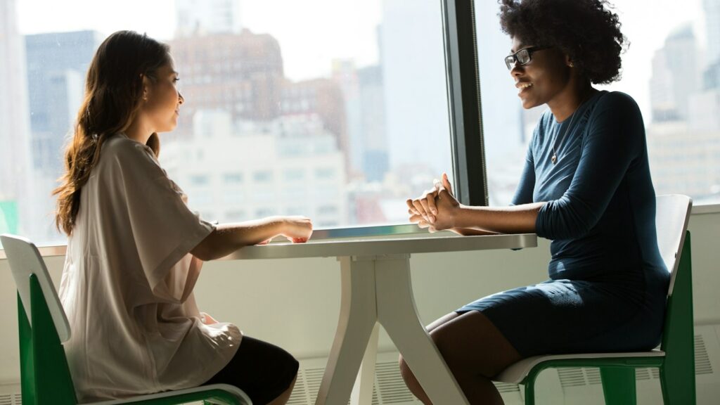 Two learners practising an English speaking activity in conversation at a table