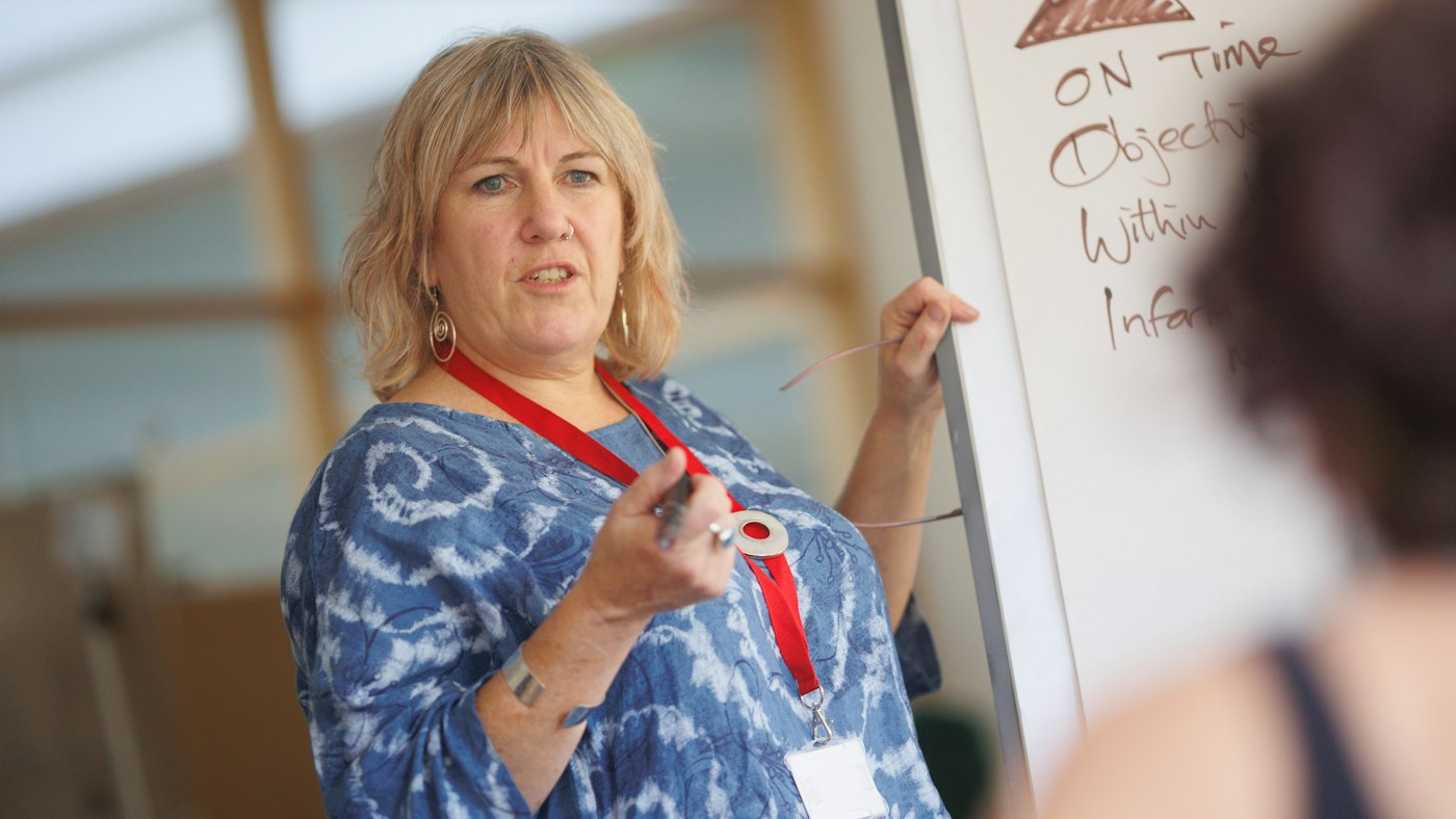 Teacher using chatgpt prompts for grammar lessons on a laptop in front of a chalkboard