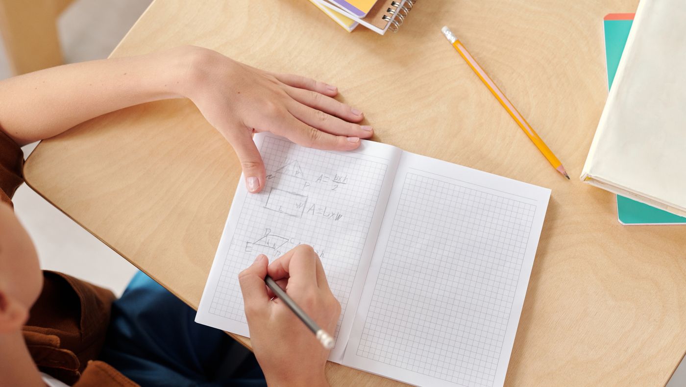 Student writing at a school desk producing process evidence against AI written homework claims