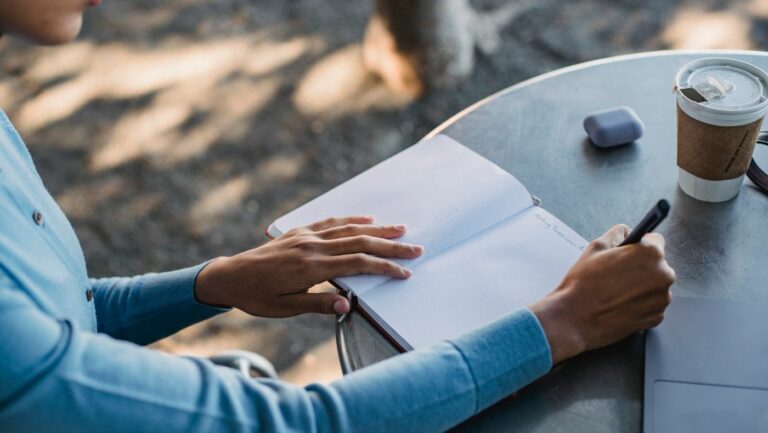Student writing an English essay by hand while teachers check for AI written work