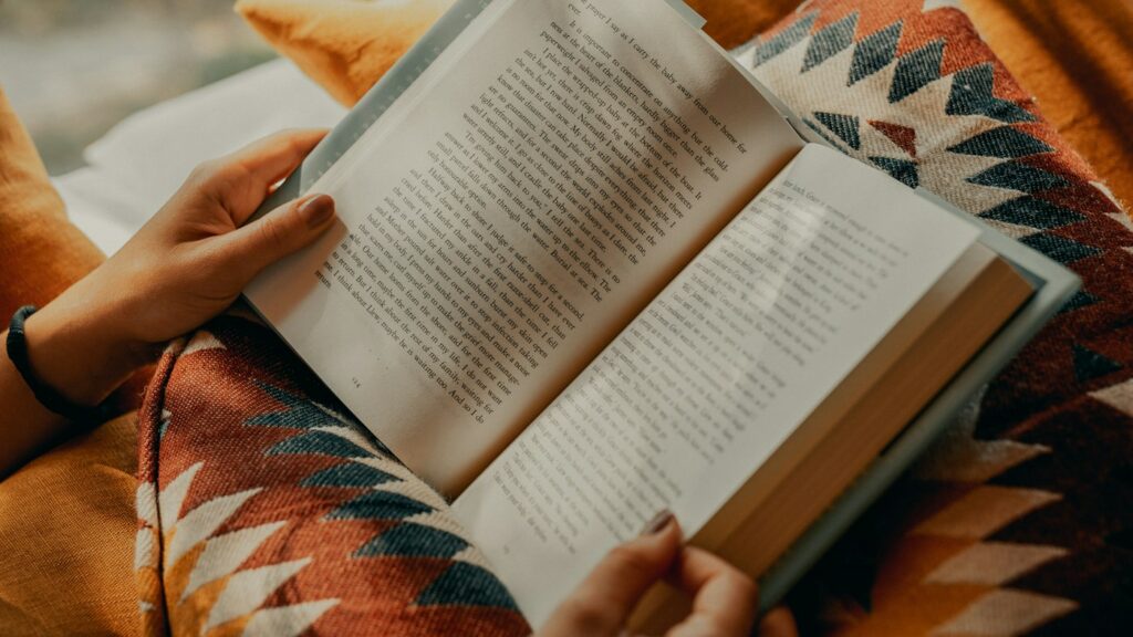 Teacher reading an English textbook while comparing AI alternatives for lesson materials