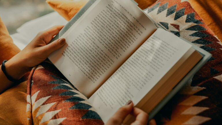 Teacher reading an English textbook while comparing AI alternatives for lesson materials